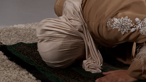 Cerca-De-Una-Mujer-Musulmana-Usando-Hijab-En-Casa-Orando-Arrodillada-Sobre-Una-Alfombra-De-Oración